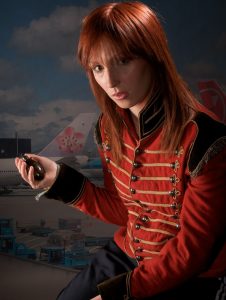 a portrait of a person with long red hair wearing a vintage soldiers' jacket