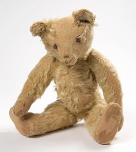 a teddy bear which has lost most of it's fur and it's nose