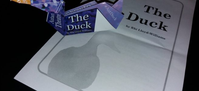 an origami duck sitting on top of a theatre playbill